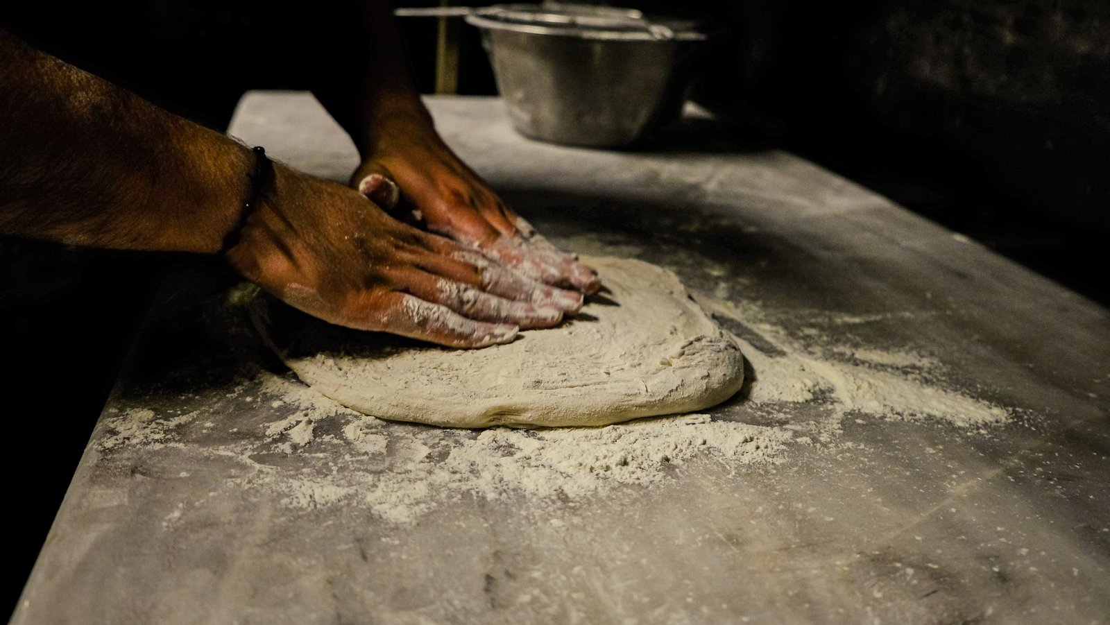 Le mani del pizzaiolo che stendono l'impasto
