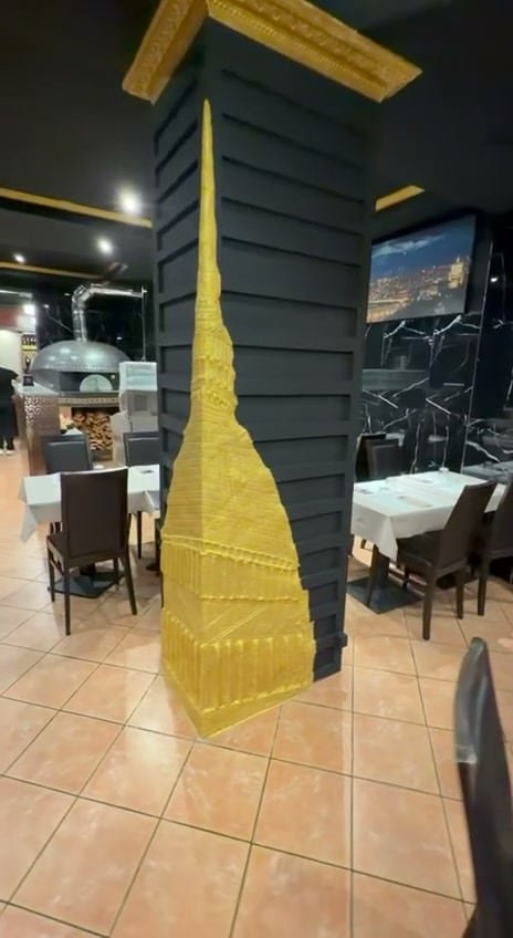 La Mole dorata sulla colonna, accanto al forno a legna